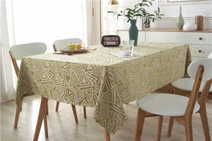 Detail of waterproof geometric jacquard tablecloth on a wooden table in a cozy dining room