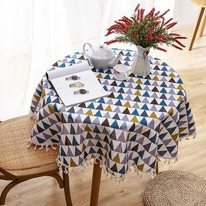 Nordic round tablecloth with geometric patterns and white fringe on a wooden table