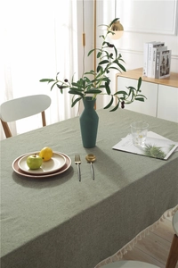 Detail of sage green linen table runner featuring delicate white fringe trim on edges