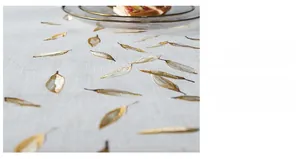 Detailed embroidery of gold leaf patterns on a grey linen textured modern tablecloth