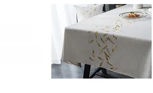 Detail showing fine gold leaf embroidery on grey linen tablecloth with precise stitching