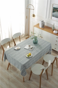 Detailed view of grey-blue linen textured tablecloth with white stripes and fringe