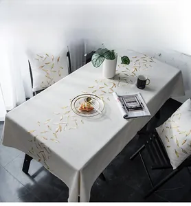 Close-up of modern beige table runner with golden feather embroidery and matching pillows