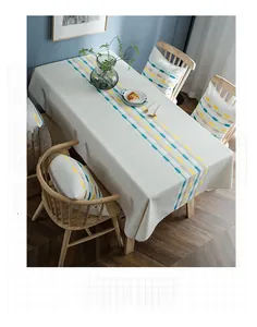 Detail of linen tablecloth with teal and yellow embroidery in a cozy dining setting