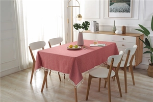 Close-up of dark red rectangular tablecloth with white fringe trim in natural light