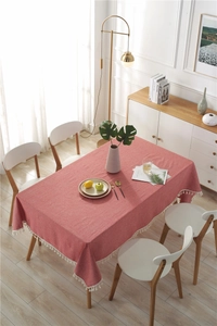 Macro detail of red rectangular tablecloth with rustic weave and white tassel edges