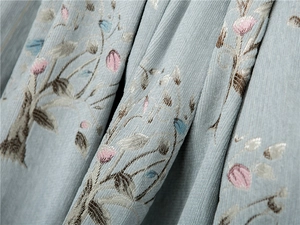 Macro view of light blue chenille fabric with floral embroidery and ribbed texture