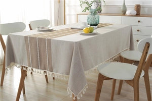 Macro detail of rectangle tablecloth featuring rustic embroidery and white tassel fringe