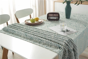 Detail of light green geometric jacquard tablecloth with textured fabric and soft drape