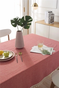 Close-up of coral red cotton-linen tablecloth texture with elegant white tassel fringe