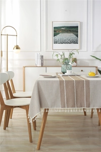 Detailed view of striped linen tablecloth fabric with delicate white fringe tassel edges
