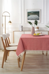 Detail of pink woven tablecloth showing cotton tassel fringe and texture on wooden table