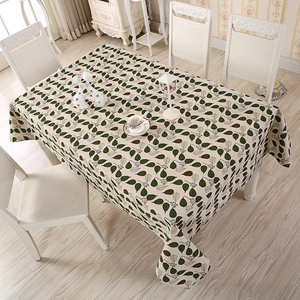 Detail of a rectangular tablecloth featuring green leaf patterns on white cotton fabric