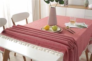 Close-up of pink cotton linen tablecloth featuring decorative white tassel fringe details