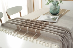 Detailed view of beige and coffee woven linen fabric with elegant white tassel fringe