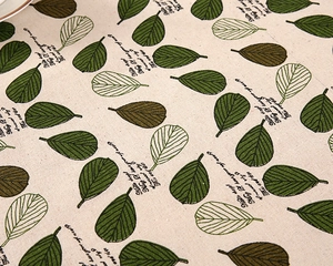 Macro detail of cotton linen tablecloth showing green leaf patterns and fabric texture