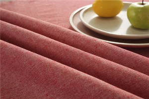 Close-up of textured red cotton linen tablecloth with tassel fringe and table setting