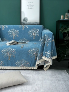 Detail of blue chenille sofa cover with tree patterns and delicate cream lace edges