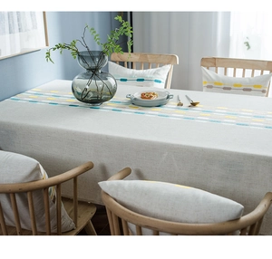 Close-up showing the linen texture and geometric embroidery of the gray tablecloth