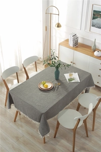 Detail of grey cotton blend tablecloth with white tassel fringe and textured fabric weave