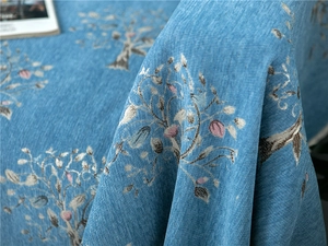 Detailed view of blue chenille fabric with floral embroidery and vertical texture