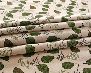 Close-up of printed cotton-polyester fabric showing green leaves and textured weave