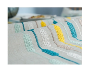 Close-up of linen fabric with detailed yellow and blue geometric embroidery on table runner