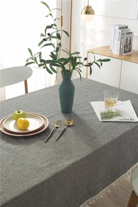 Close-up of grey linen tablecloth with white fringe tassels in a modern home setting