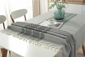 Close-up of gray jacquard table cloth with white tassels and minimalist stripe patterns