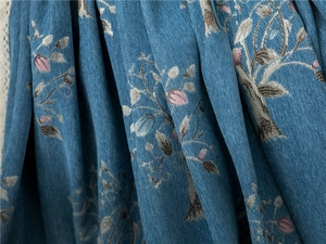 Detail of blue chenille sofa cover showing leaf embroidery and soft velvet texture