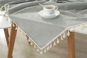 Detail shot of grey linen texture tablecloth featuring white fringe edges and woven pattern