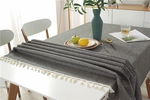 Detail of dark grey woven tablecloth showing fabric texture and white tassel edges