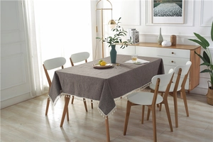 Close-up of greyish brown cotton linen tablecloth with elegant white fringe details
