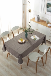 Detailed close-up of dark coffee linen tablecloth with elegant white tassel trim