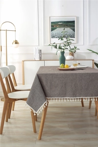 Detail of minimalist coffee-colored rectangular tablecloth with white tassel fringe edges