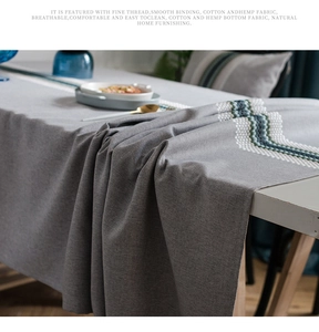 Close-up of modern linen table runner with blue geometric embroidery and textured fabric