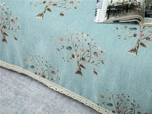 Close-up of thick chenille sofa cover with tree embroidery and white lace edges