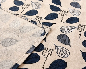 Close-up of blue leaf pattern and stitched edge detail on linen tablecloth