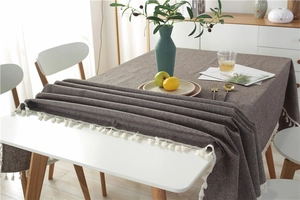 Detailed close-up of dark brown cotton linen tablecloth with elegant white tassels edge