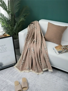 Detail of chenille sofa cover showing leaf embroidery and white lace floral trim