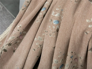 Detail of thick chenille sofa cover with floral embroidery and white lace trim
