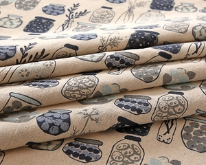 Close-up of linen-blend tablecloth featuring printed blue kitchen jars and floral patterns