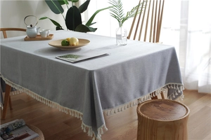 Close-up of light gray linen tablecloth featuring delicate cream tassel edge details