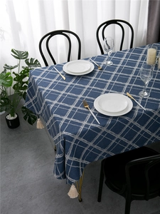Detail of blue plaid tablecloth with white tassels and elegant dining table setting