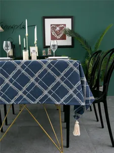 Detail of navy blue plaid tablecloth with decorative tassels on a modern dining table