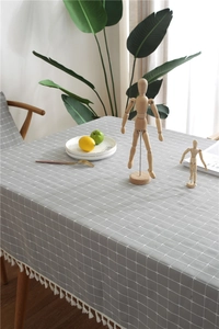 Close-up of grey plaid tablecloth featuring white grid patterns and delicate fringe edges