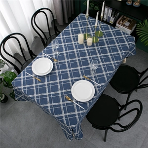 Detail of navy blue plaid tablecloth featuring white grid patterns and beige fringe tassels