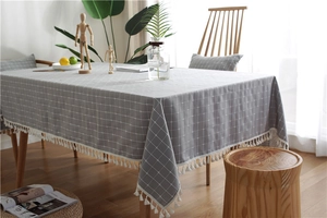 Close-up of grey plaid tablecloth with white fringe tassels and textured fabric