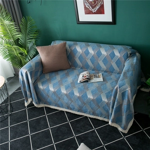 Detail of blue geometric chenille sofa cover with golden patterns and lace edges
