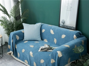 Detail of blue chenille sofa cover with yellow ginkgo leaf pattern and white lace trim